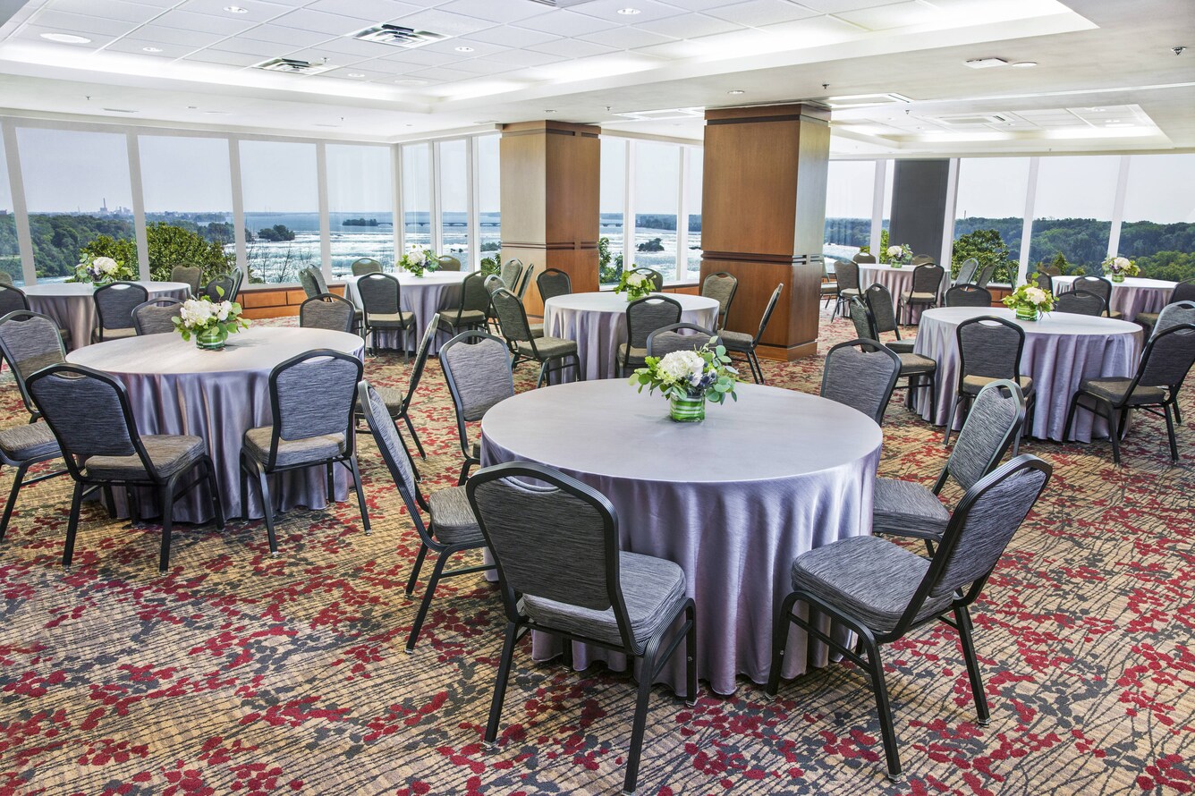 small round tables with chairs surrounding, windows overlooking the falls in the background