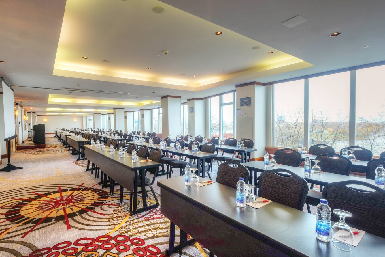 a series of long tables facing a lectern in front of windows overlooking the falls