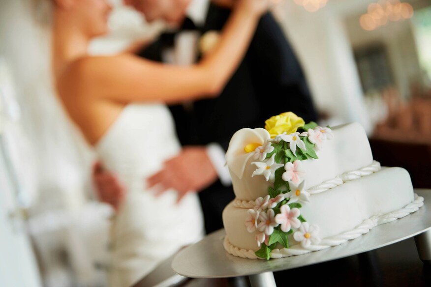 Bride and Groom dancing in background. Wedding cake in foreground
