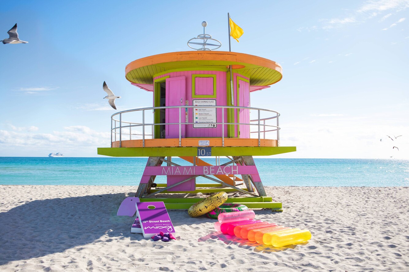 Round lifeguard hut painted pink with green trim and multi-colored floaties.