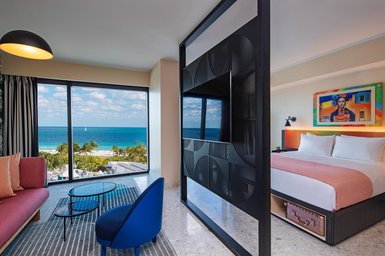 King bed with floor to ceiling windows, room divider, and ocean views