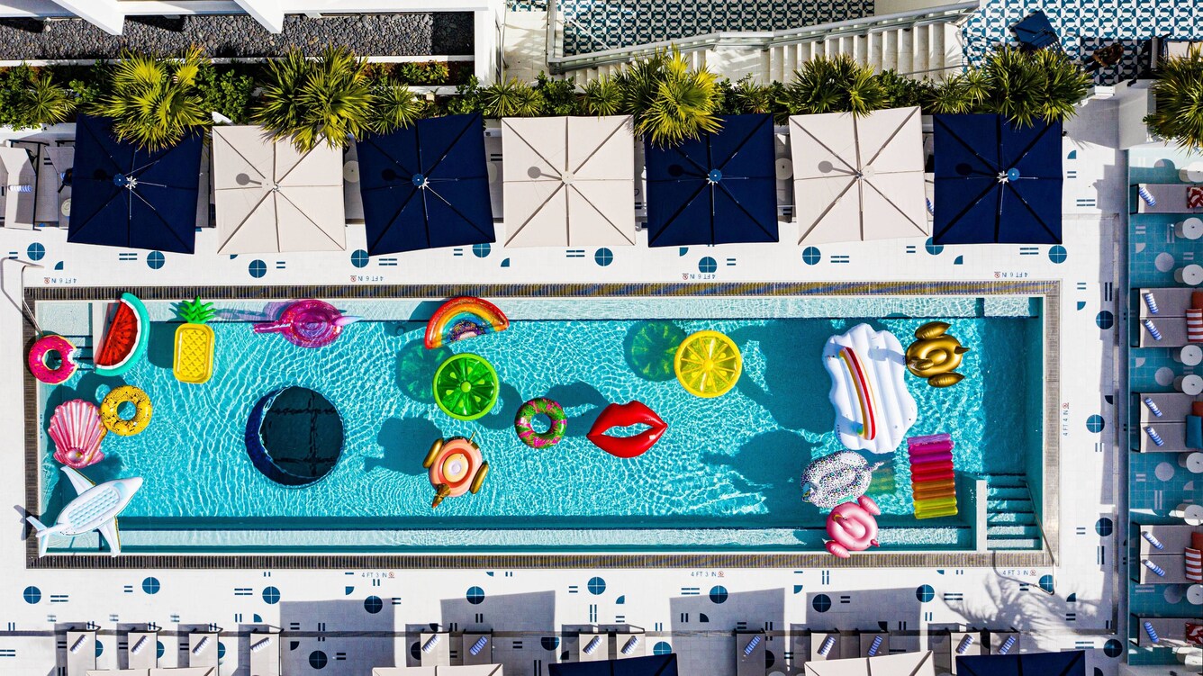 Aerial view of pool with multicolorful pool floaties and umbrellas