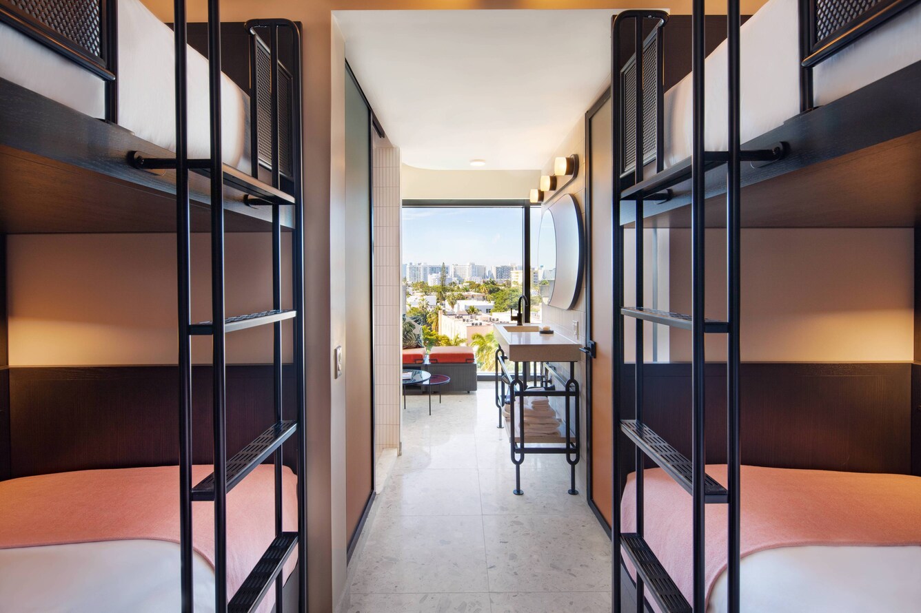 Quad bunk bed room with black ladders, and sitting area with floor to ceiling windows