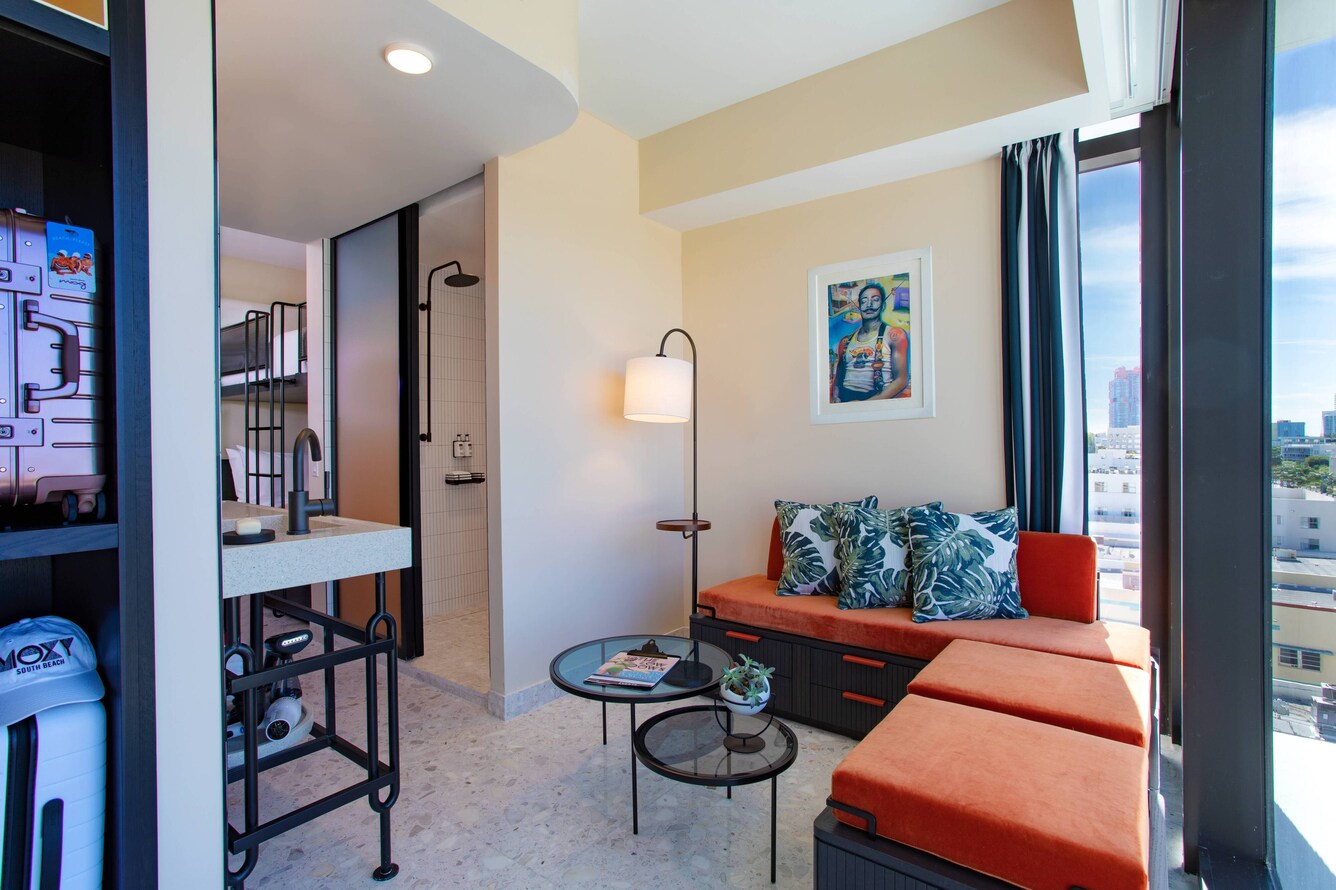 Moxy miami quad bunk bed deluxe room with sitting area and view of miami.