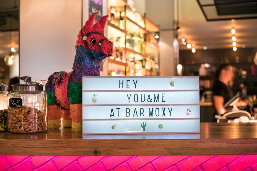 Multicolored donkey pinata on bar with sign that says "Hey You and Me at Bar Moxy"