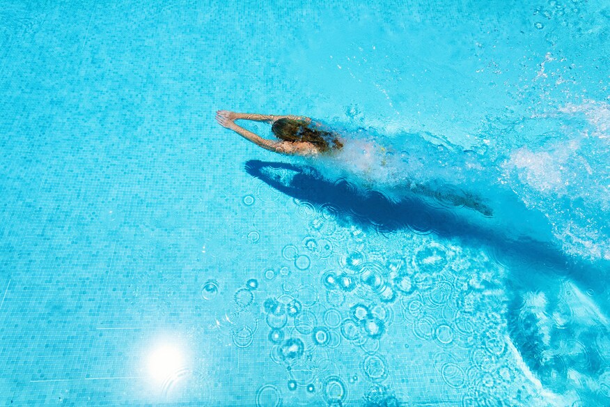 Woman in a pool swimming underwater.