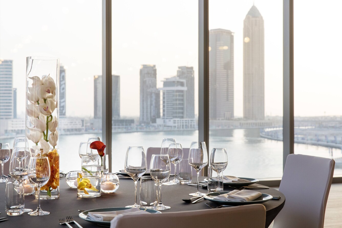 Set table in front of window overlooking waterfront cityscape at day time.