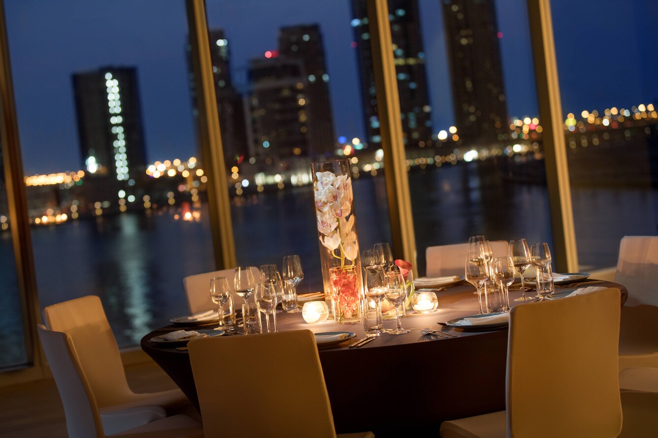 Candlelit table in front of window overlooking waterfront cityscape at night