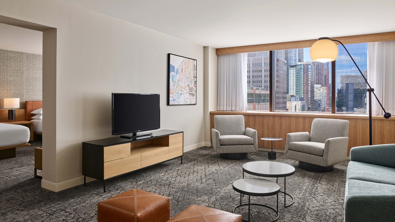Suite living area with large window overlooking city.
