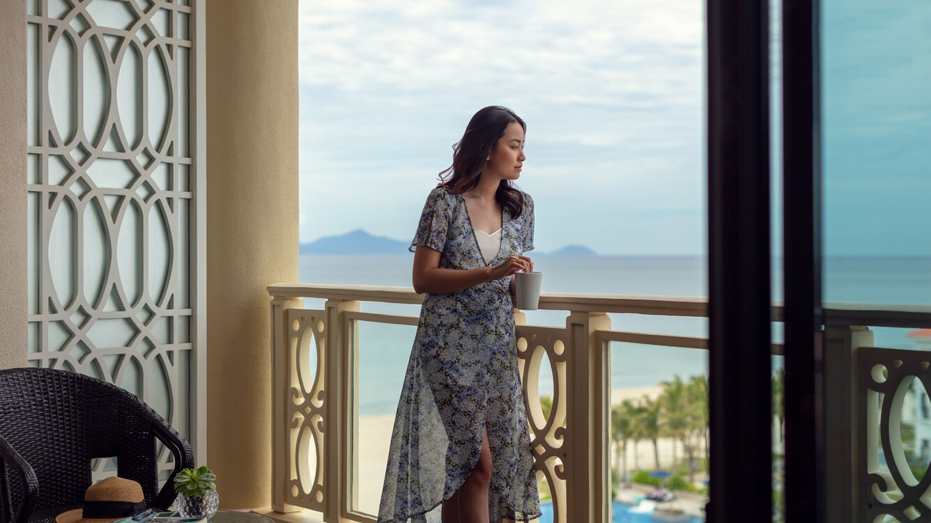 Woman standing on the balcony of her room overlooking the resort.