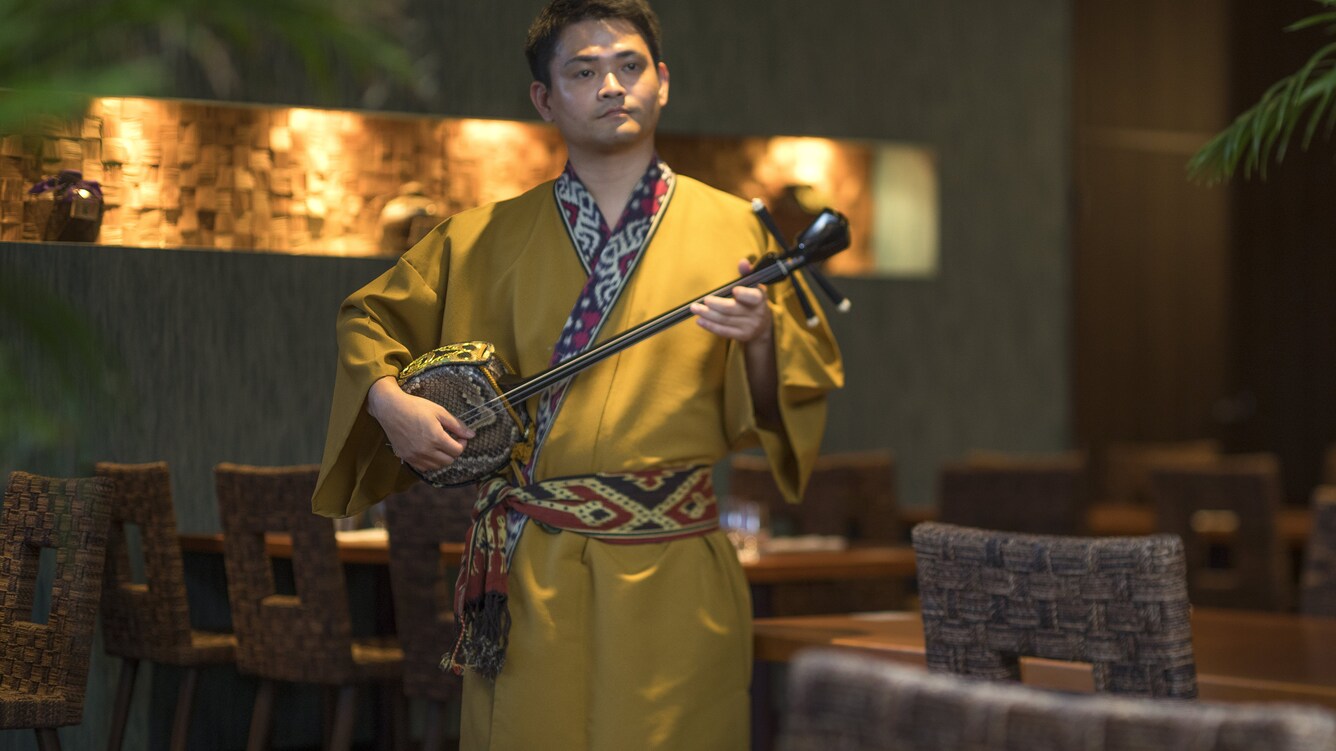 Man playing traditional sanshin instrument