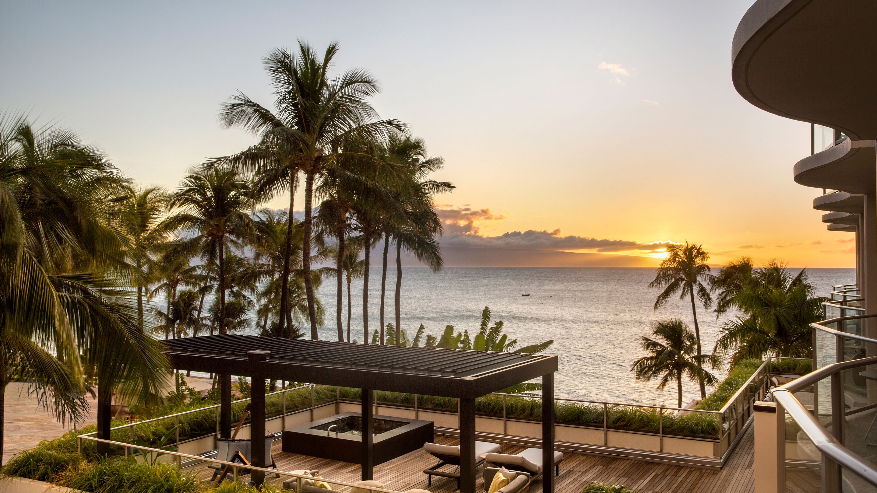 Large deck with a view of the ocean and sunset.