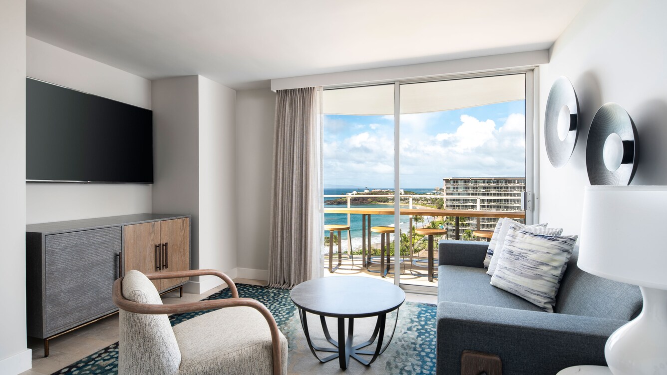 Premier Suite living area, chairs, flat screen and view of the balcony.