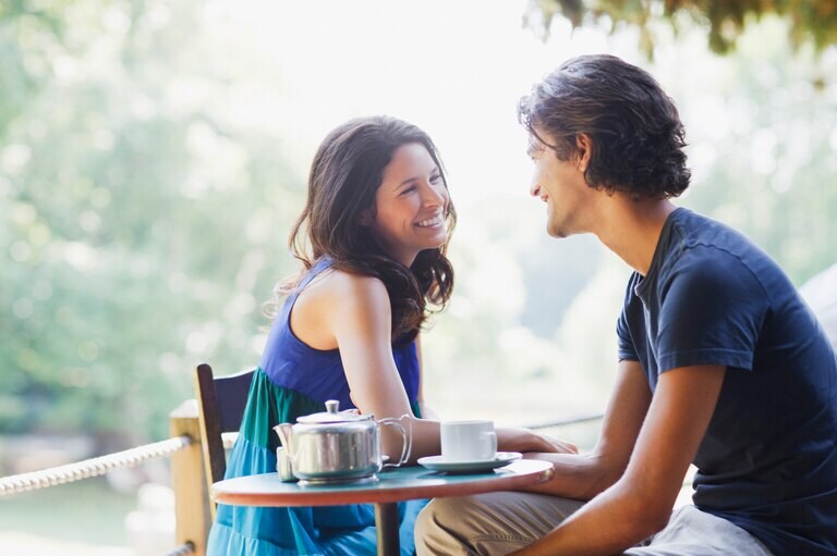 A couple having coffee at a small outdoor table.