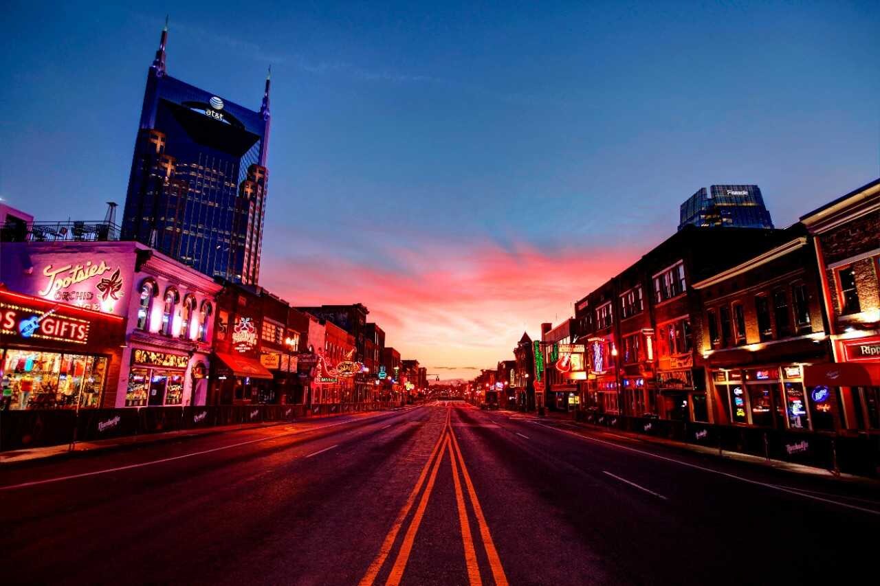 City street at sunset with neon-lit storefronts and colorful signs.