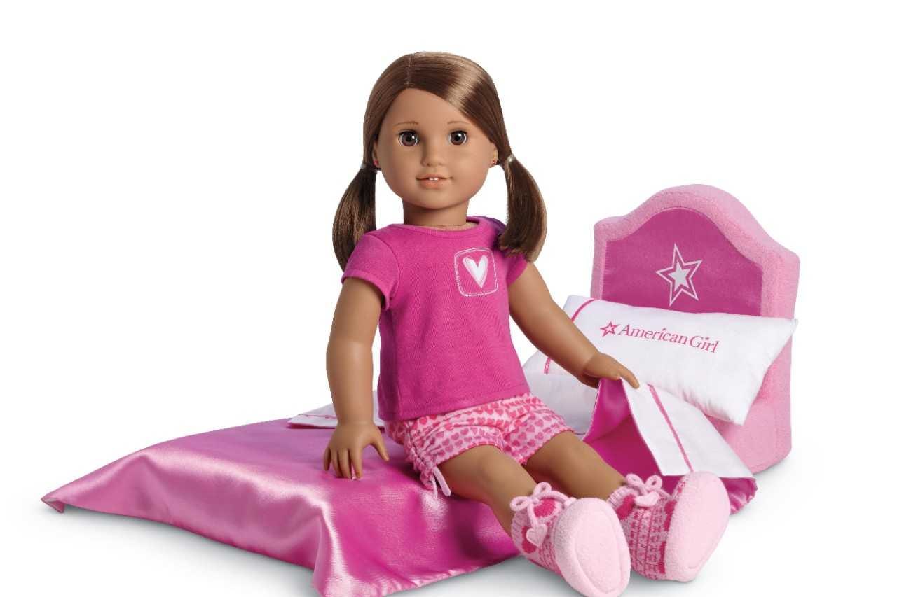 American girl doll sitting on doll bed.