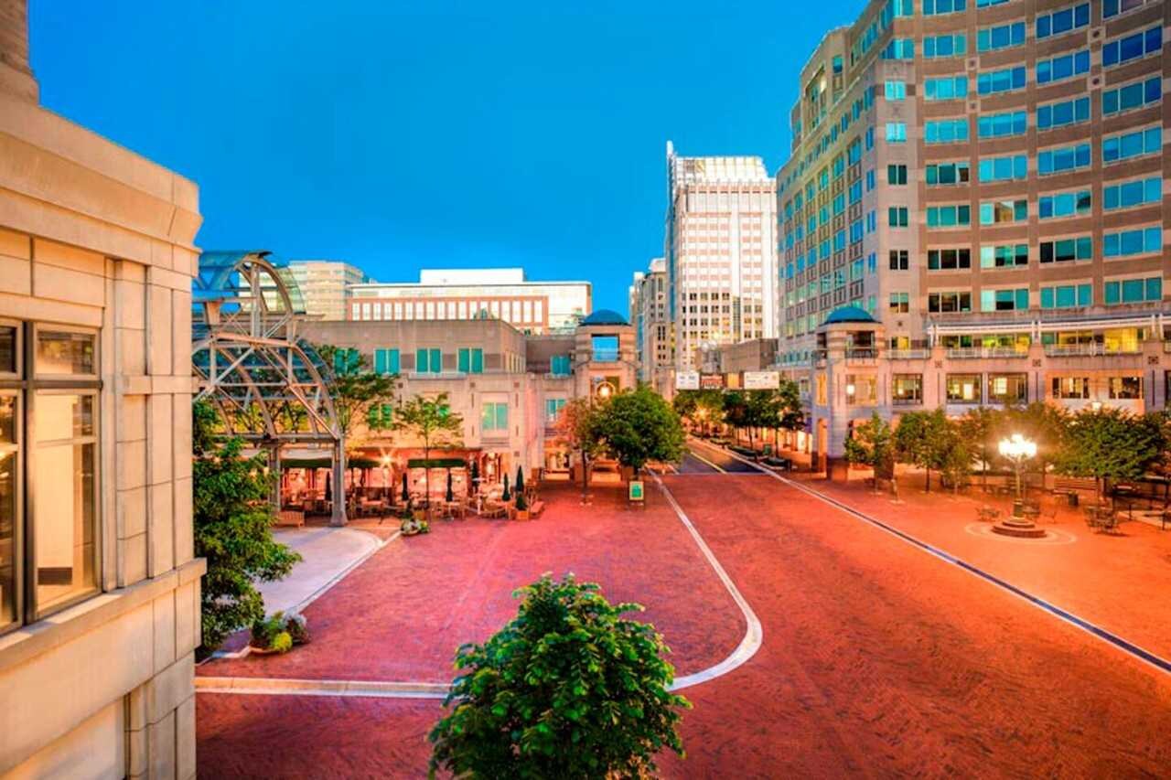 Downtown city streets with trees and outdoor patios, surrounded by skyscrapers.