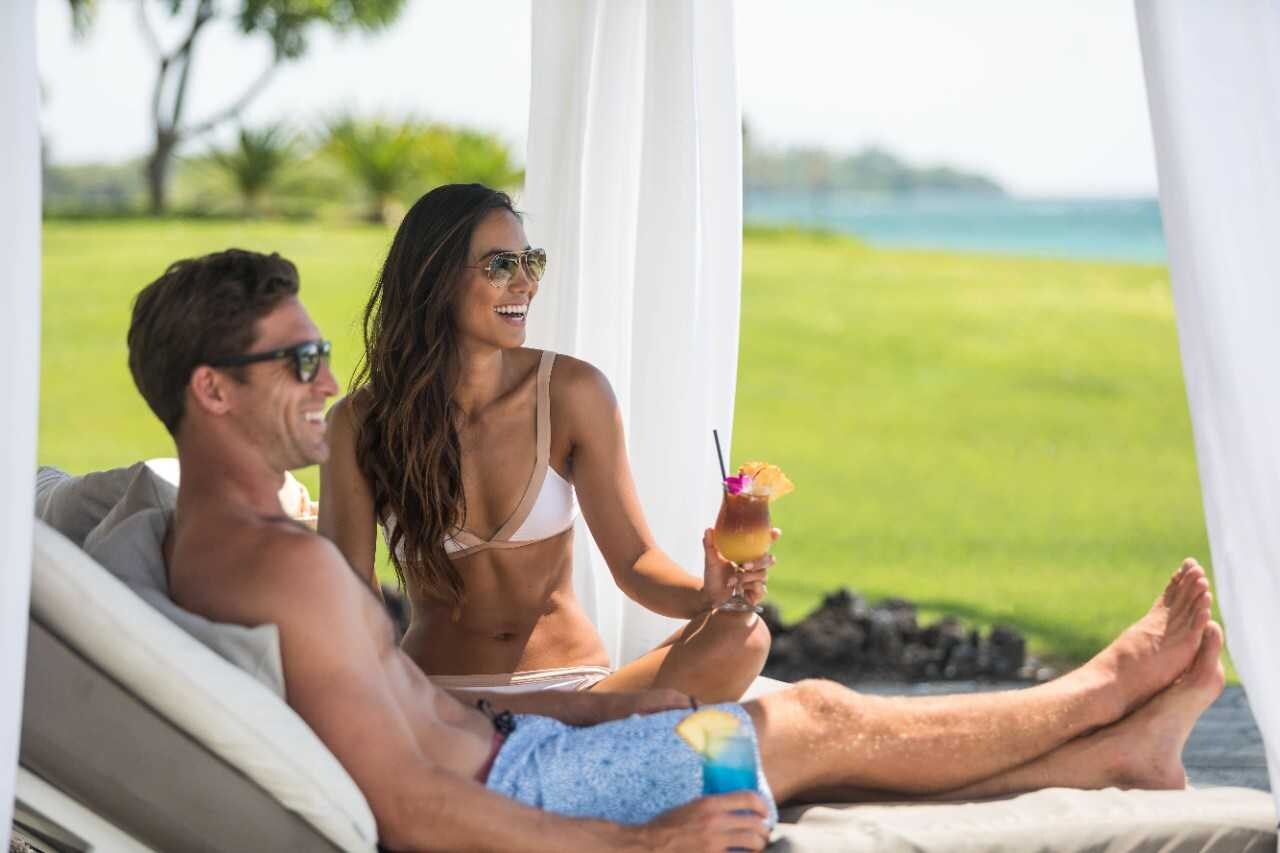 Couple sitting in a cabana enjoying tropical treats