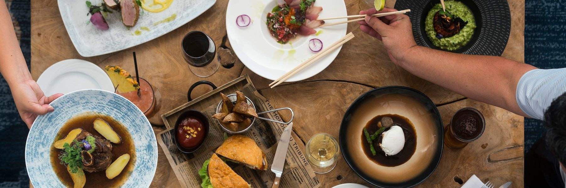 Variety of food dishes on a table and person using chopsticks