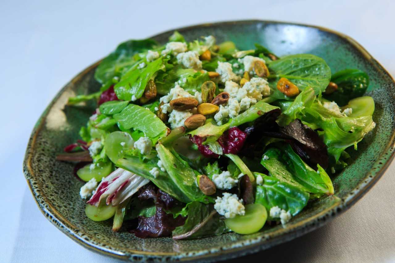 Salad with feta and spinach on a dark ceramic plate