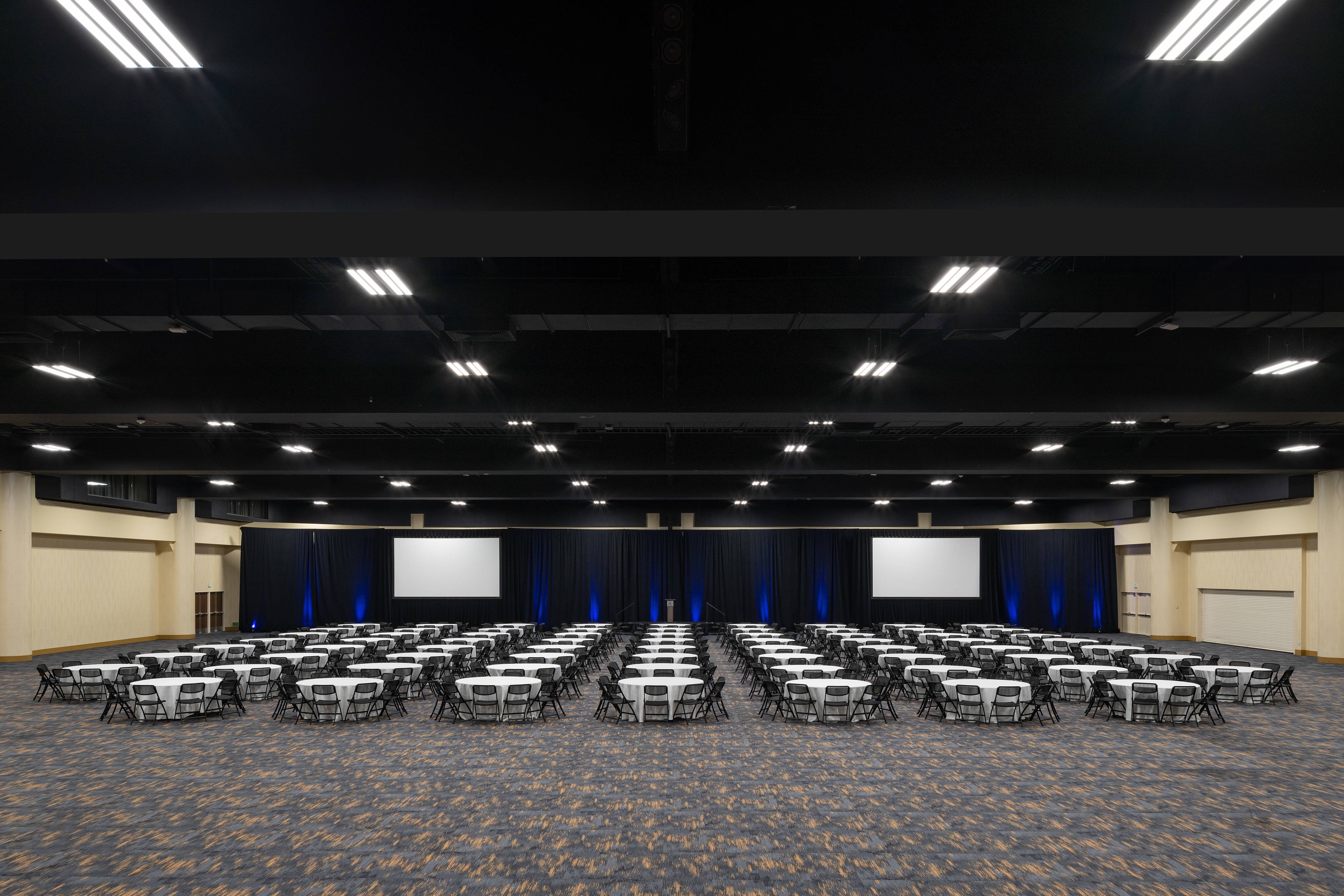 West Exhibit Hall theater setup with dozens of round tables