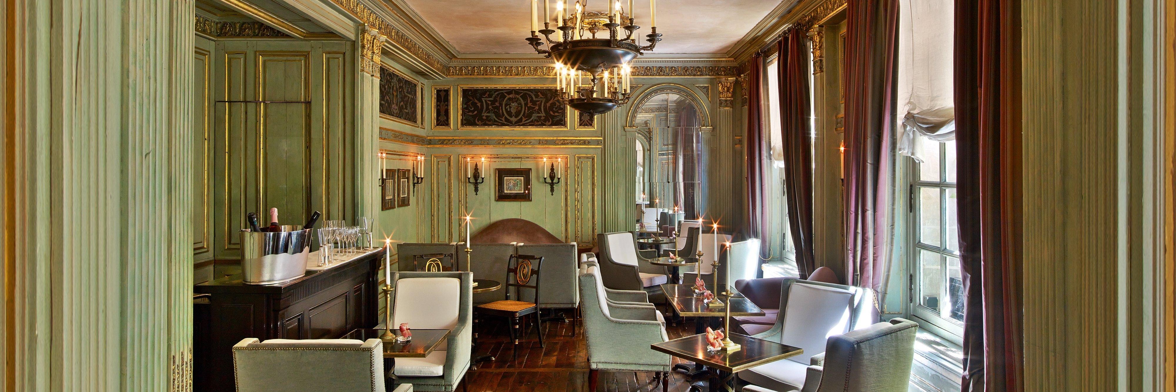 Bar lounge with pale green wood paneling, wall sconces, and champagne glasses on the bar.