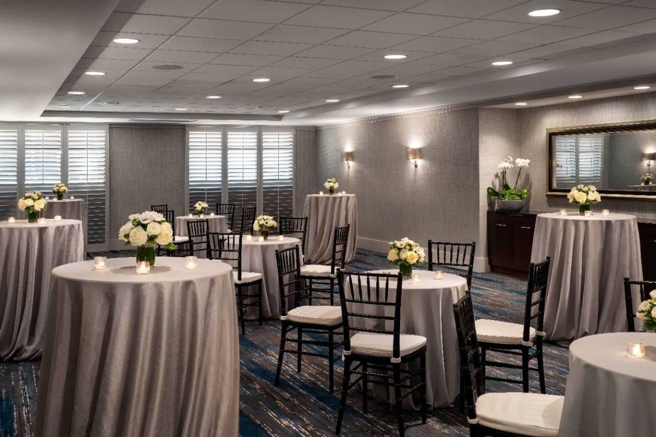 Ballroom tables decorated with white linens, white flower bouquets, and candles.