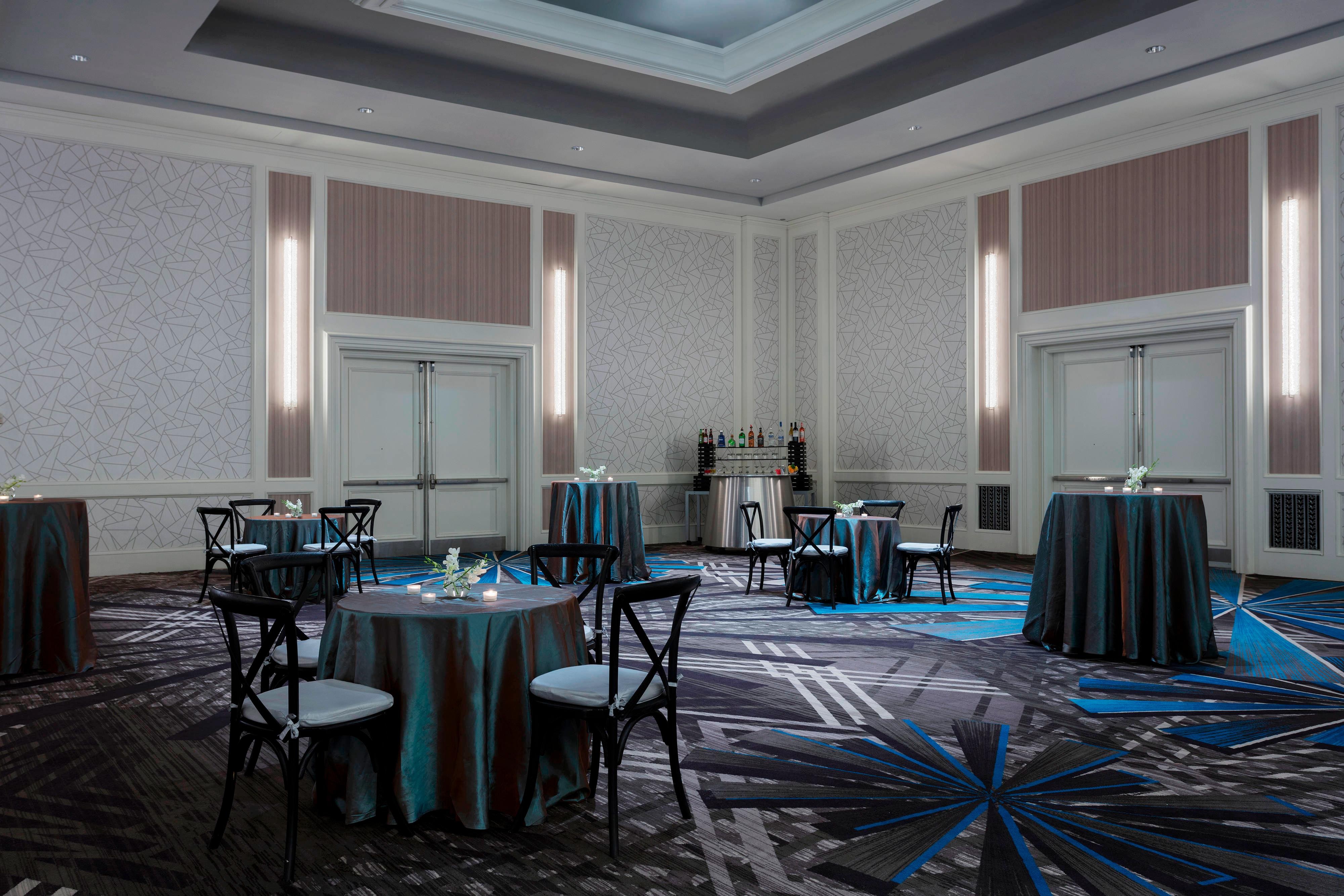 Ballroom with round tables set with white flower arrangements and tealights