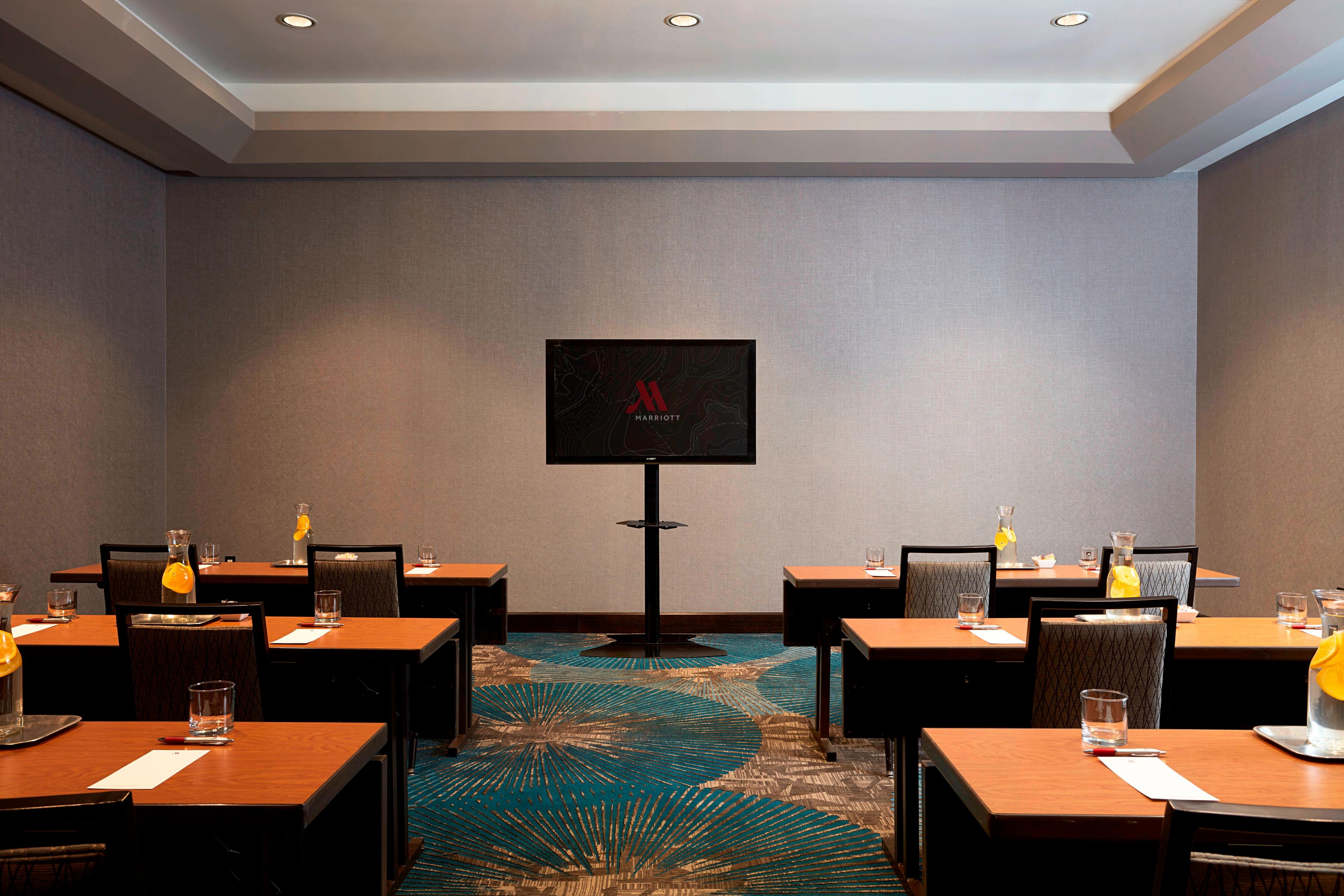 Meeting room classroom setup with tables set with carafes of citrus water and notepads
