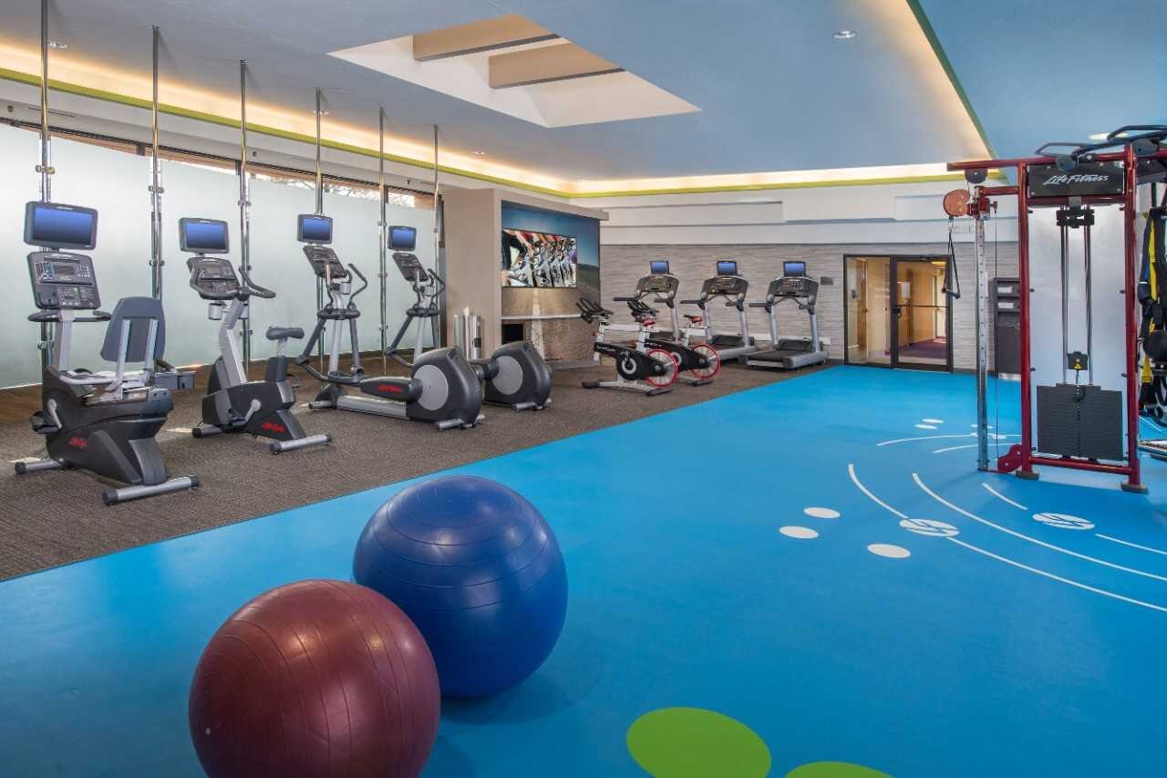 Fitness room with cardio machines, stability balls, and weight training equipment.