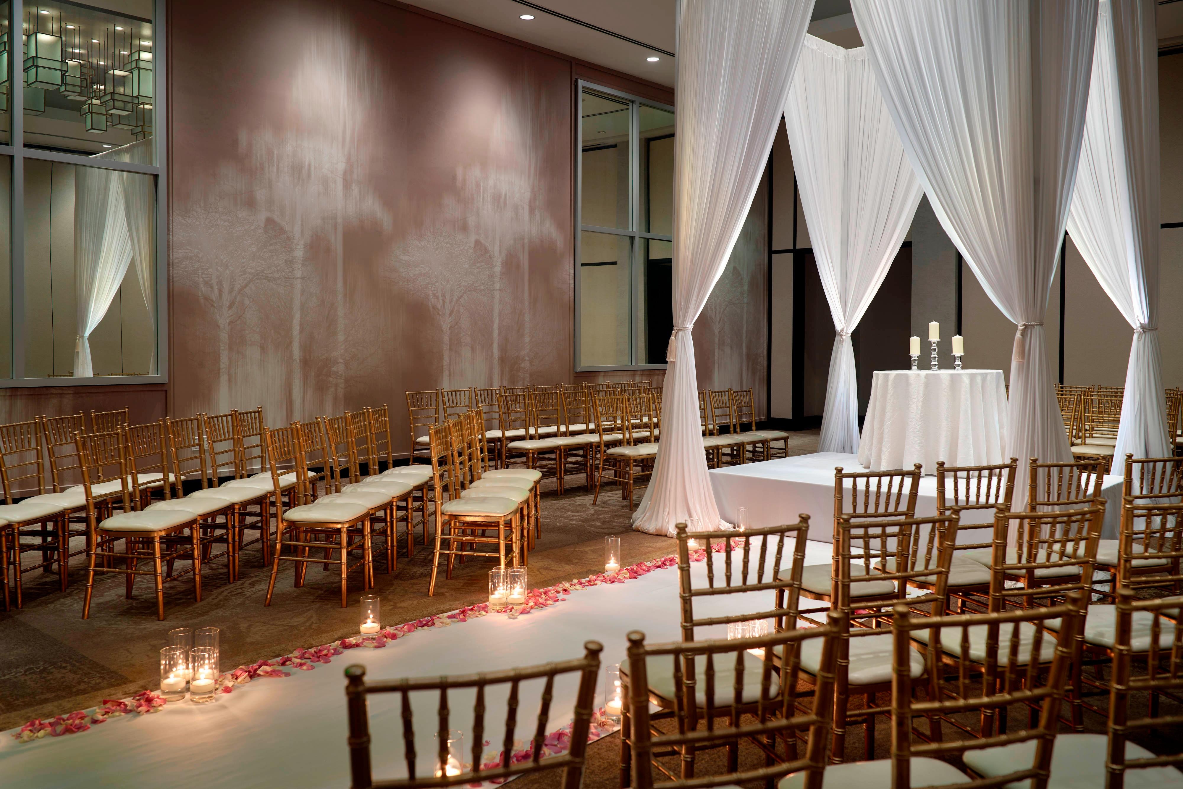 Ballroom wedding ceremony with low stage and white drapes