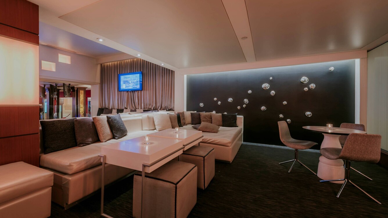 Dimly lit lounge with tables and couches.