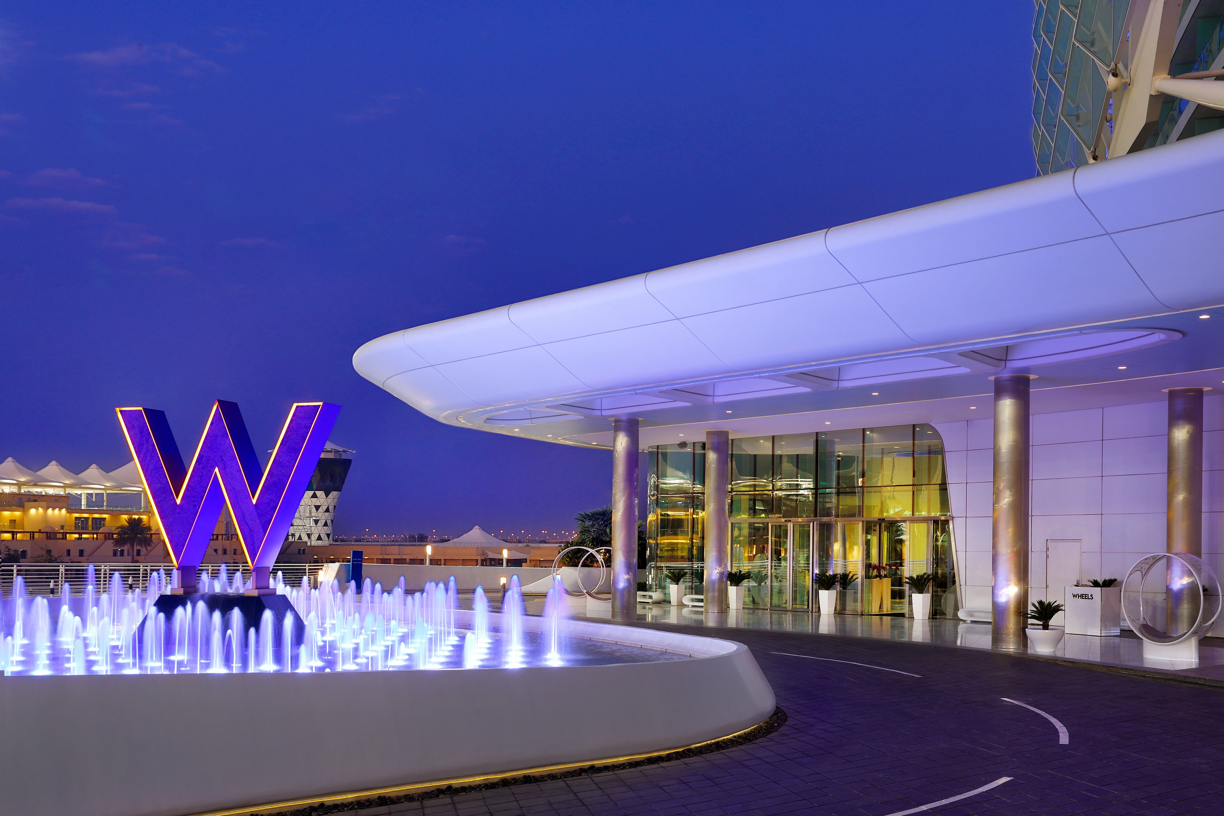 W sign and fountain lit with blue lights at night
