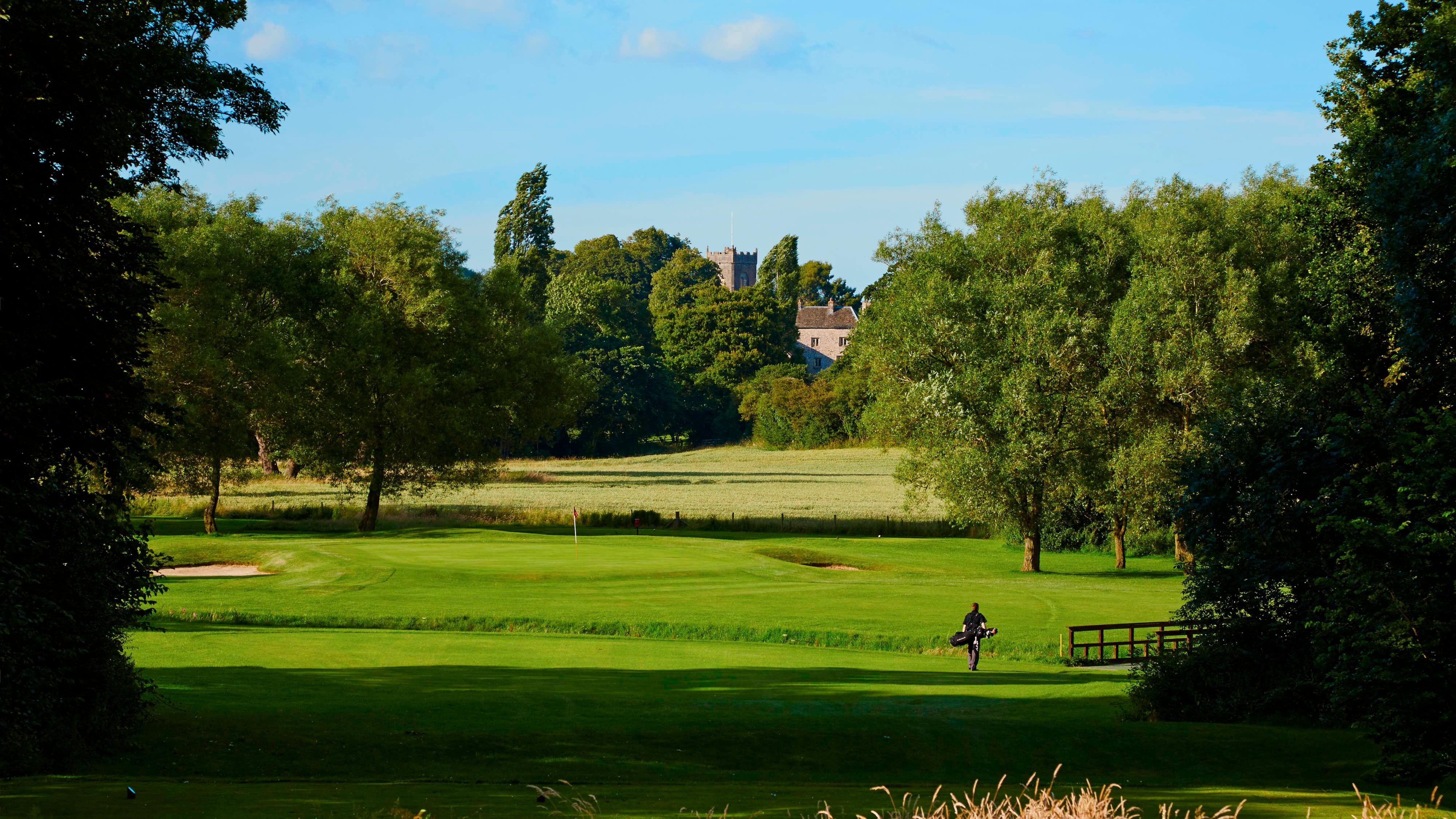 Person carrying golf bag on golf course