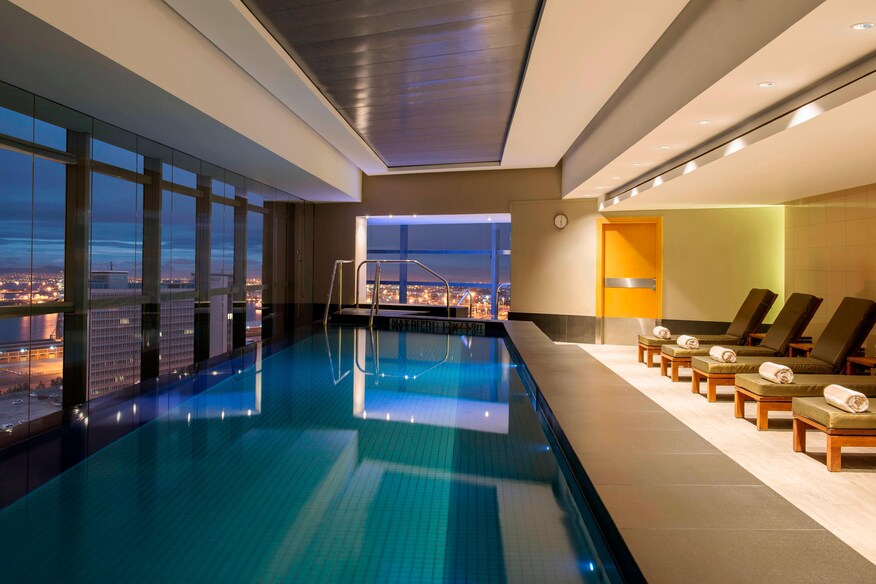 Indoor infinity pool next to windows with city view.