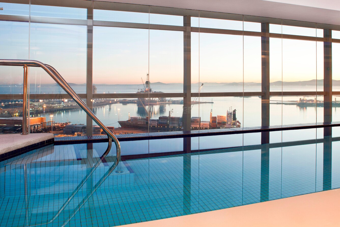 Indoor infinity pool next to windows of city view.