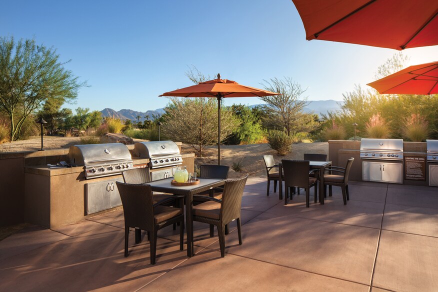 Grill area, view of three grill units, patio seating, and umbrellas.