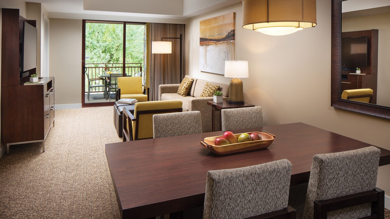 Villa living area and dining table with view of outdoors through window.