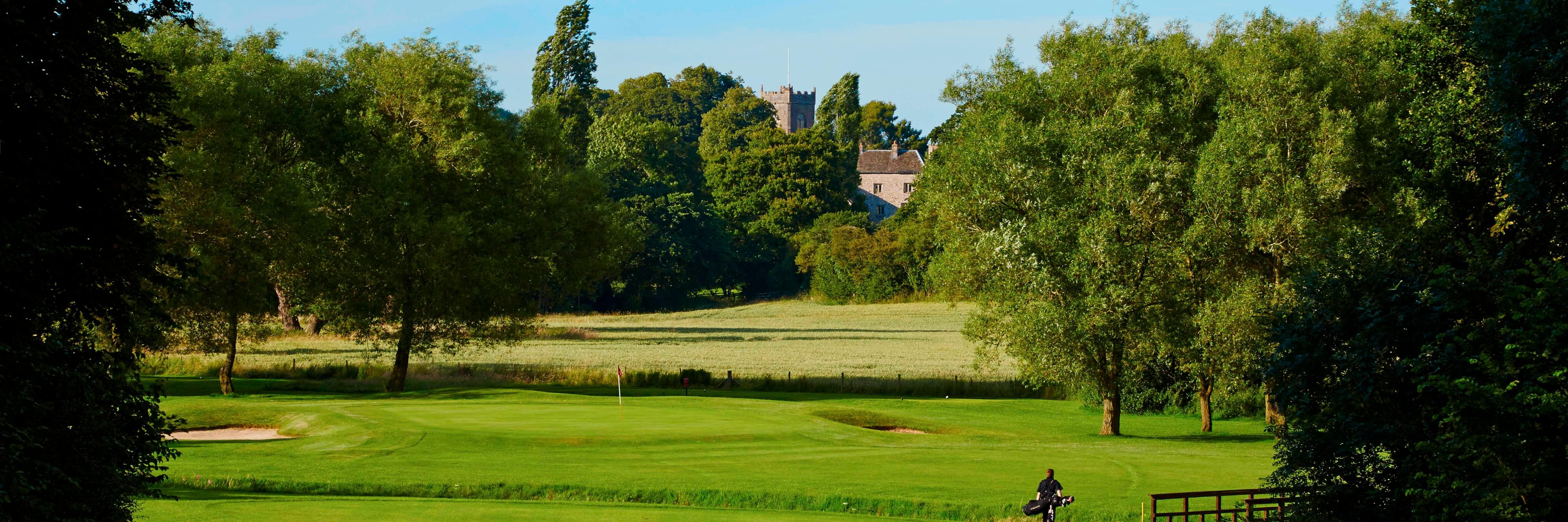 Person carrying golf bag on golf course