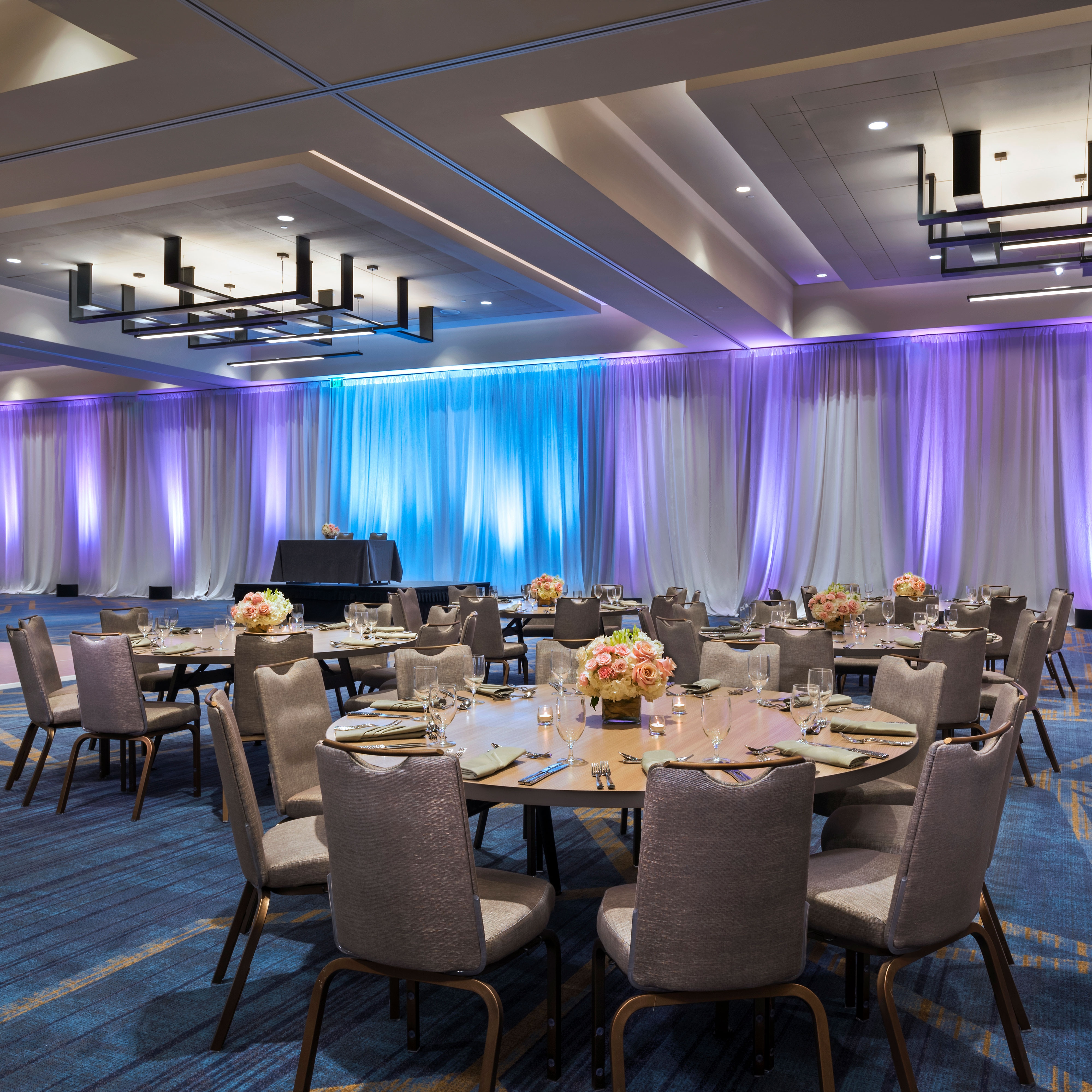 Ballroom wedding reception setup with blue and purple accent lighting