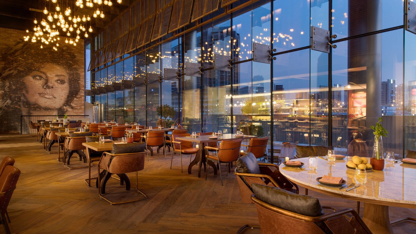 Large dining area with floor-to-ceiling windows and large portrait of Sophia Loren.