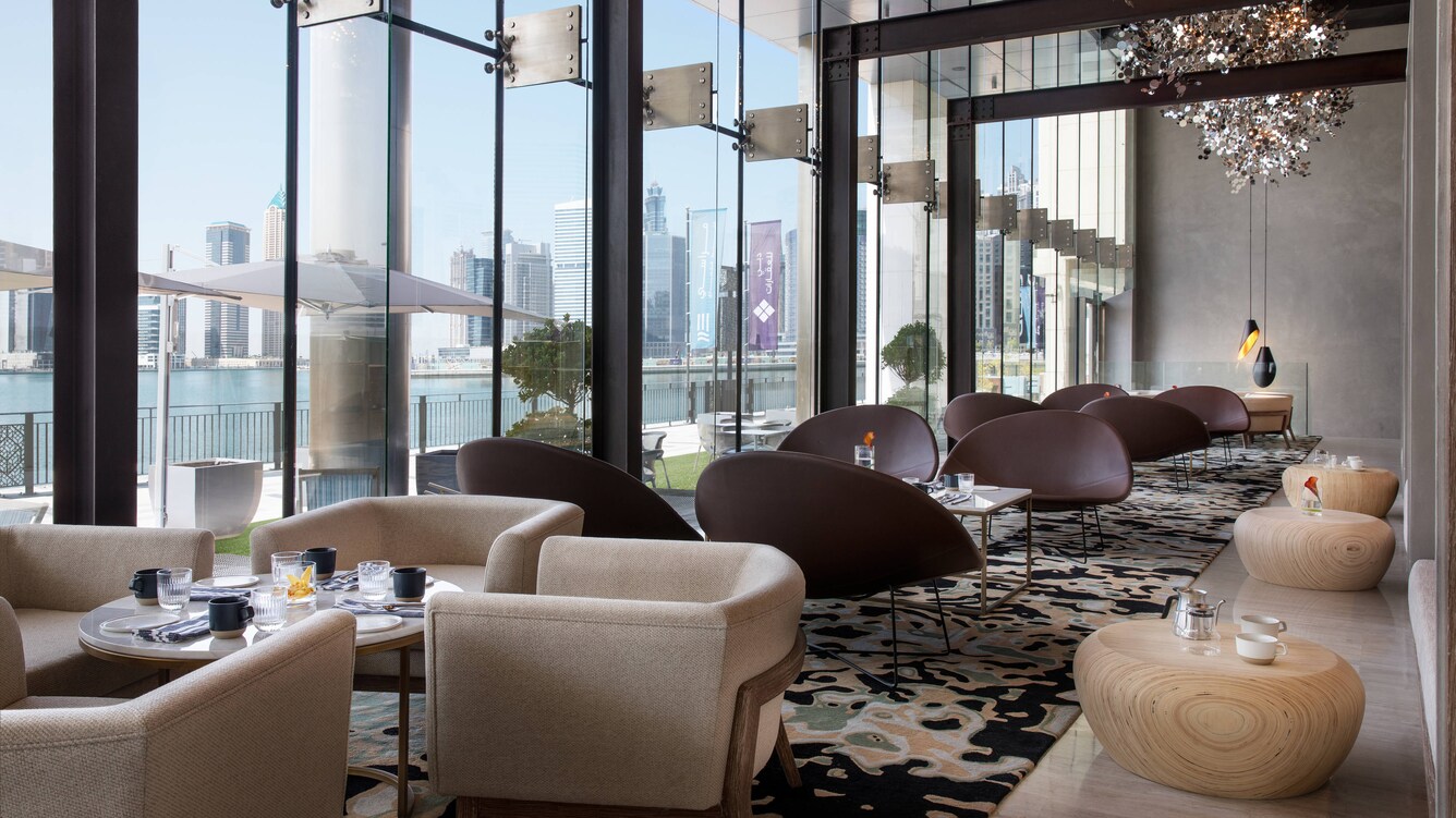 Lounge area with floor-to-ceiling windows and low, comfortable chairs.