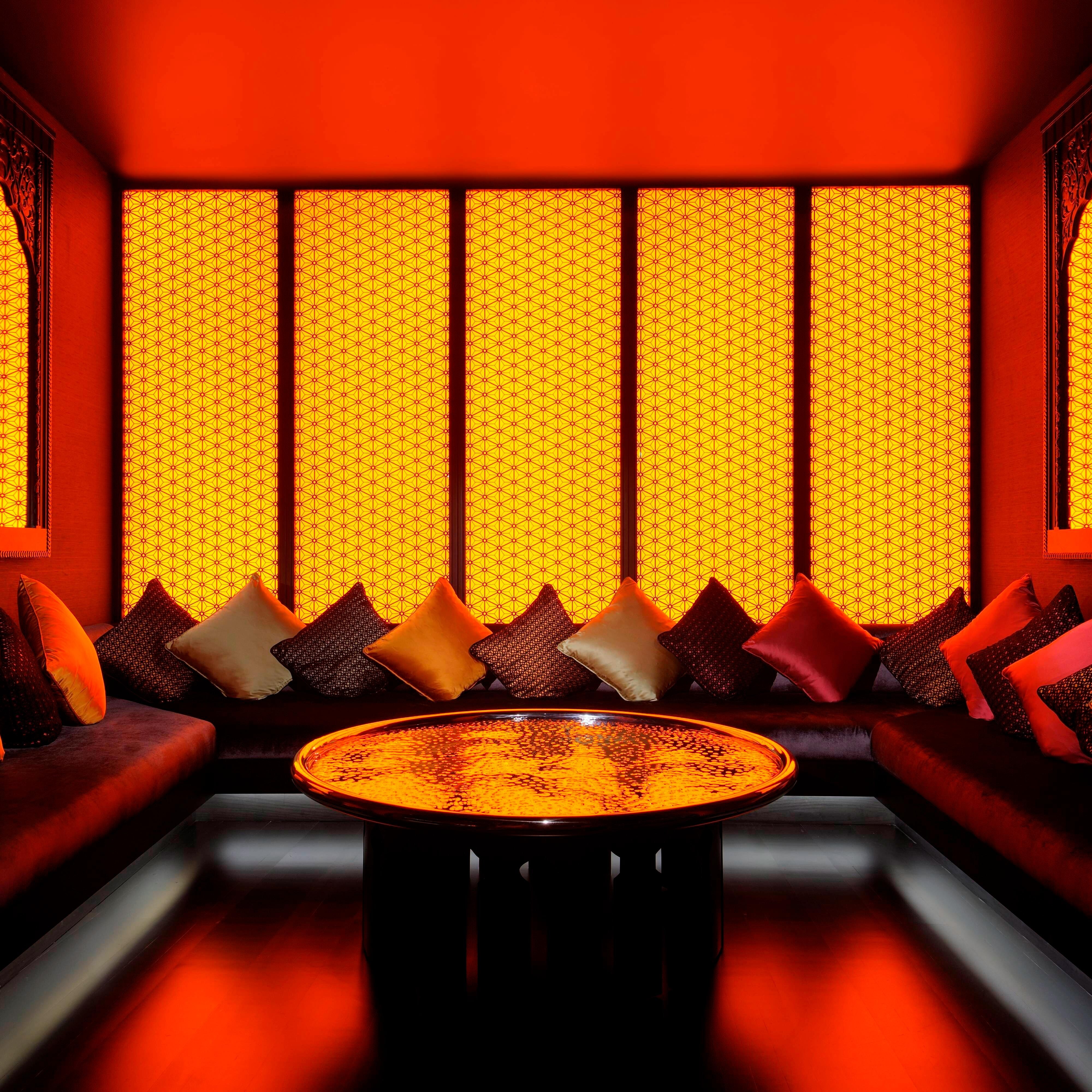 A dining room booth filled with cushions and lit with yellow and orange light