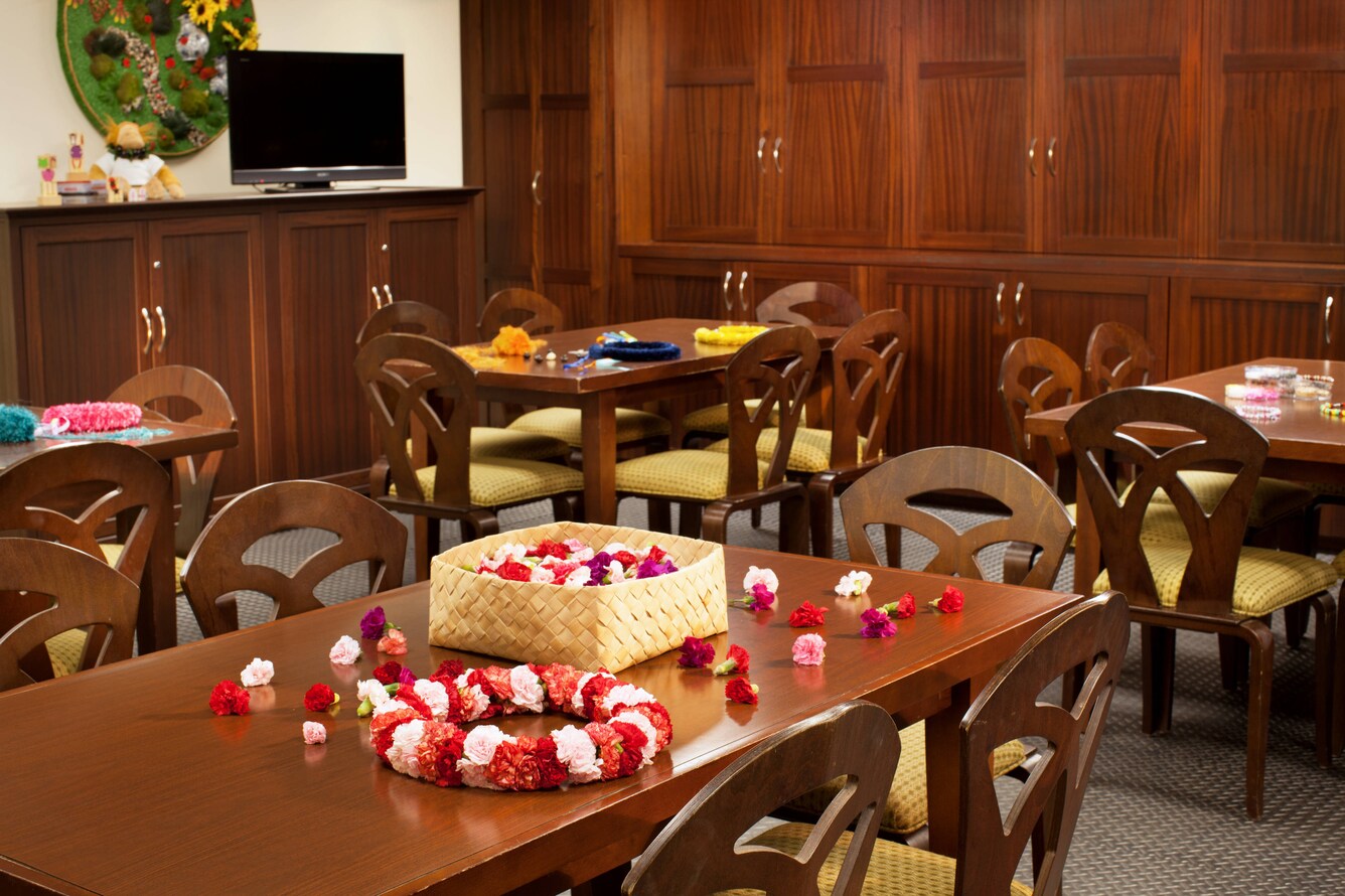 Table with flowers in a basket for crafting leis.