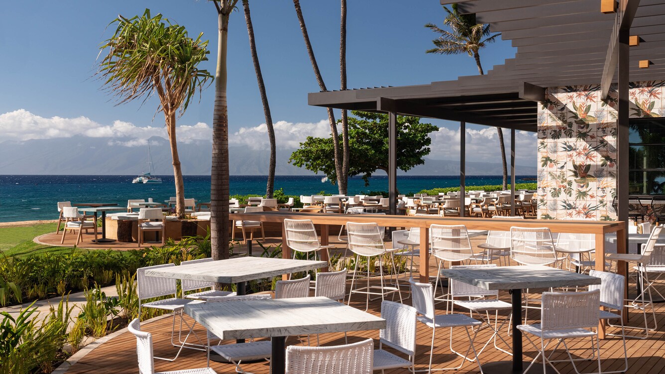 Outdoor deck seating with the ocean in the background.