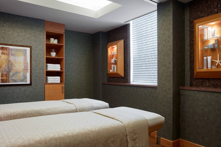 Massage room with two massage tables and low lighting.
