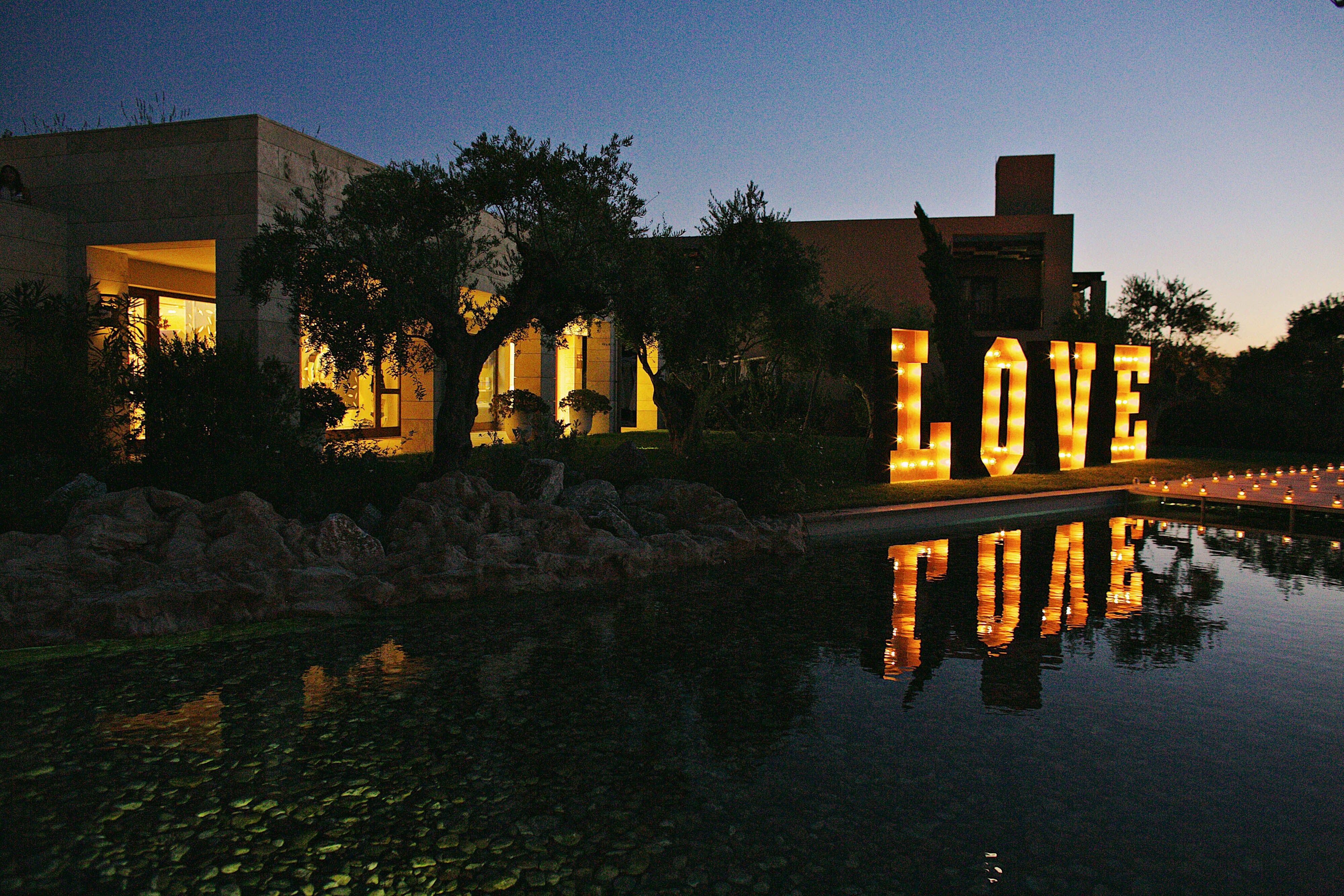 Hochzeitsfeier im Freien mit beleuchtetem Schild, das die Aufschrift "Love" trägt