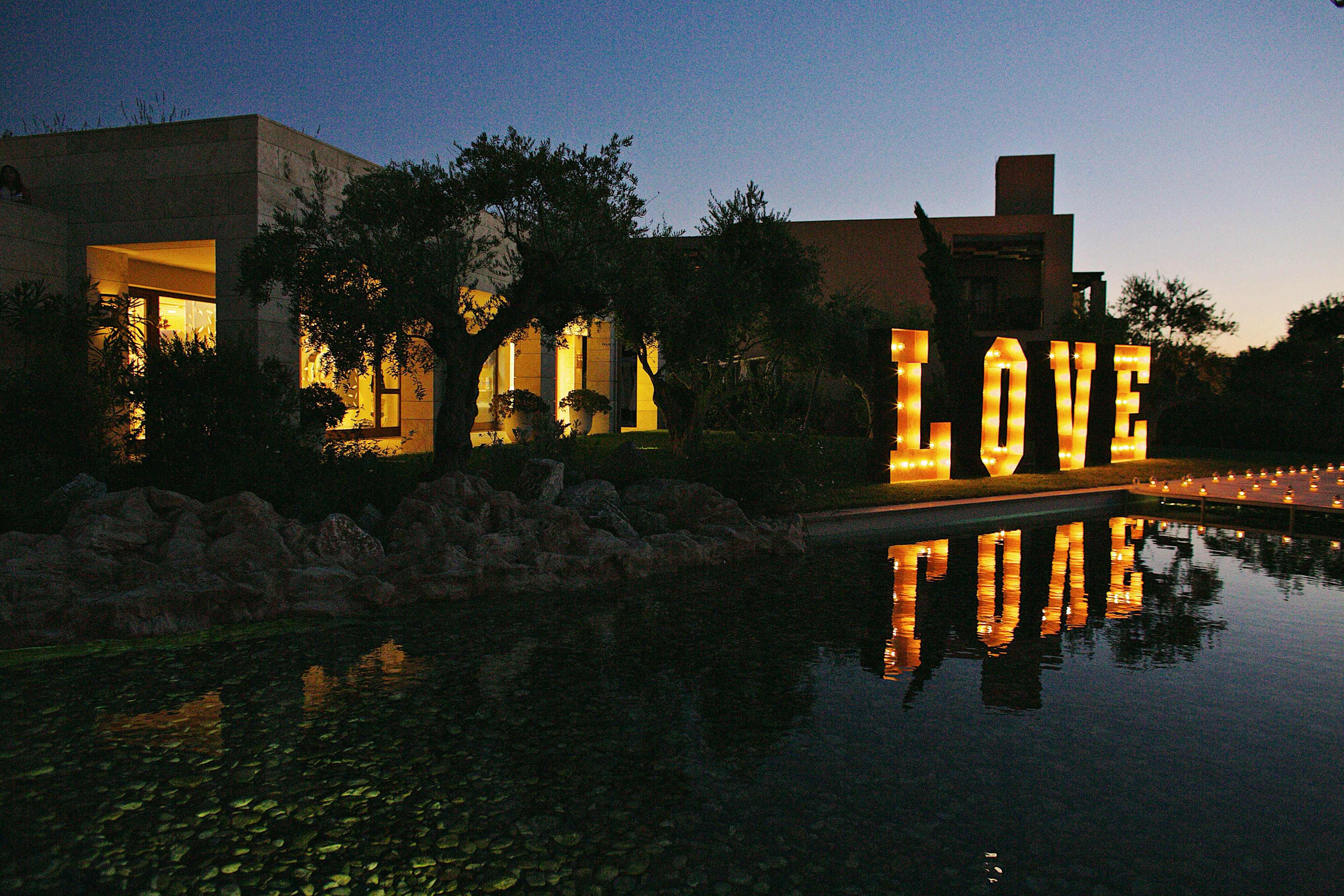 Outdoor wedding party with lit-up sign spelling Love