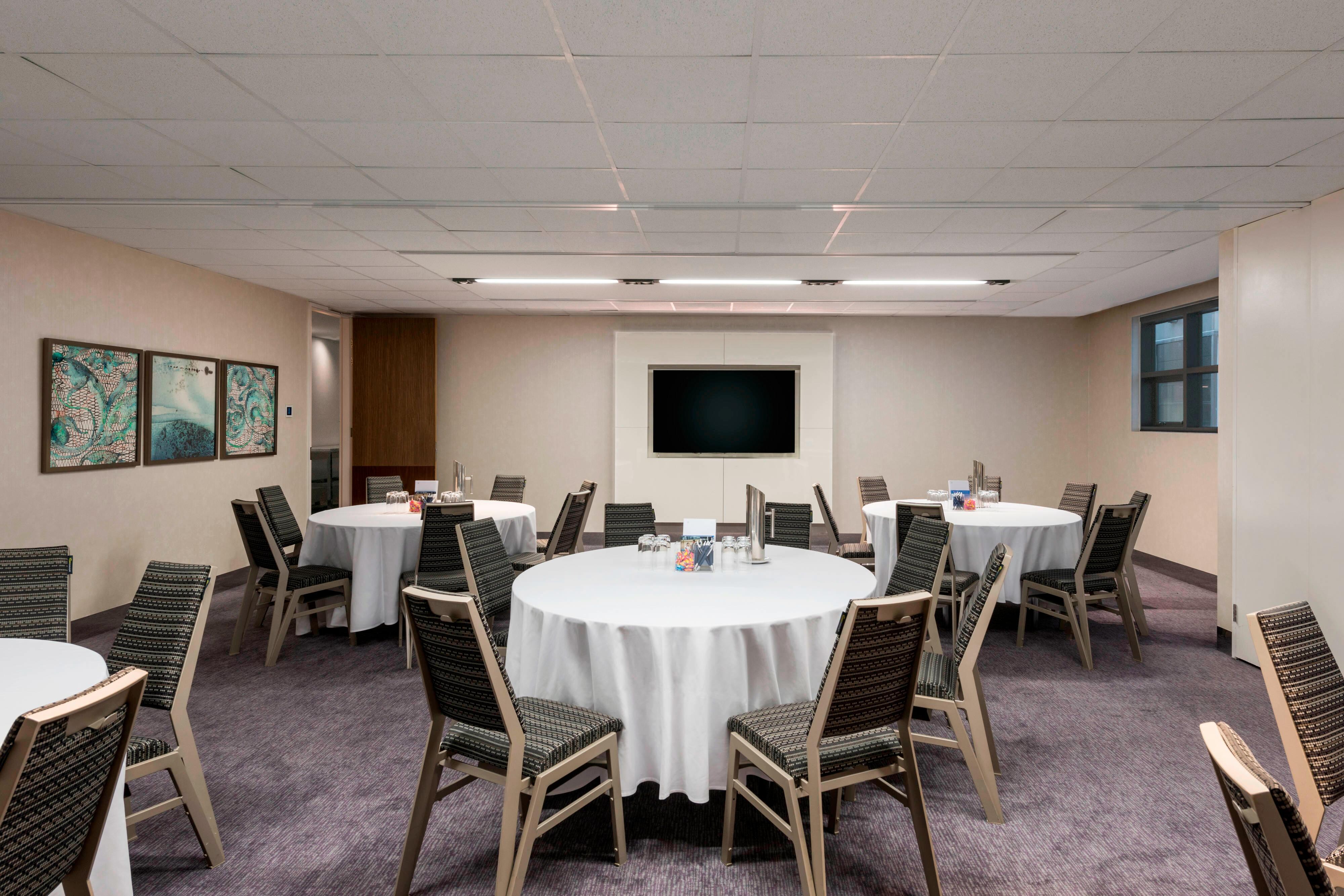 Meeting room set up with round tables and television screen
