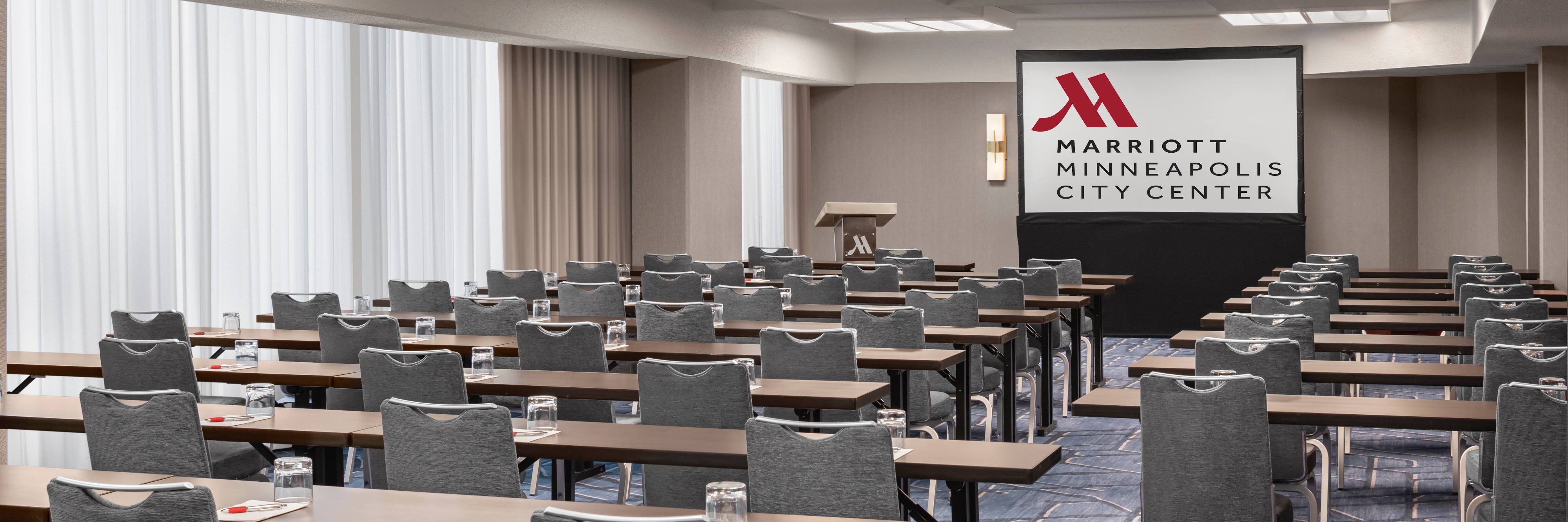 Meeting room with rows of tables and chairs and a projector screen